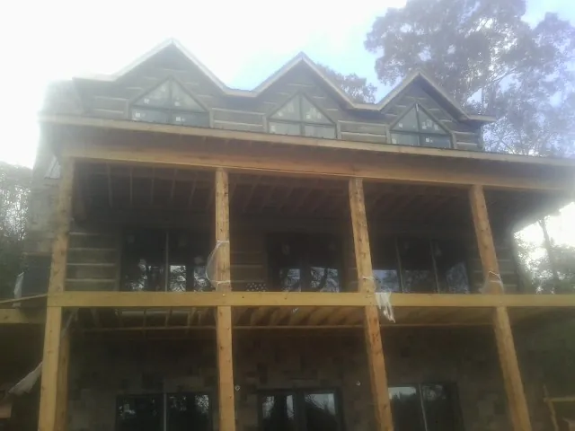 Dormers and porch framing on a large log home under construction — Roof Coating work by our crew in Upsala