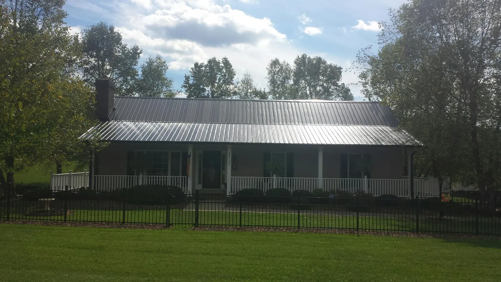 Gray metal roof on a brick ranch with a full width front porch — Gutter Guard Installation work by our crew in Upsala