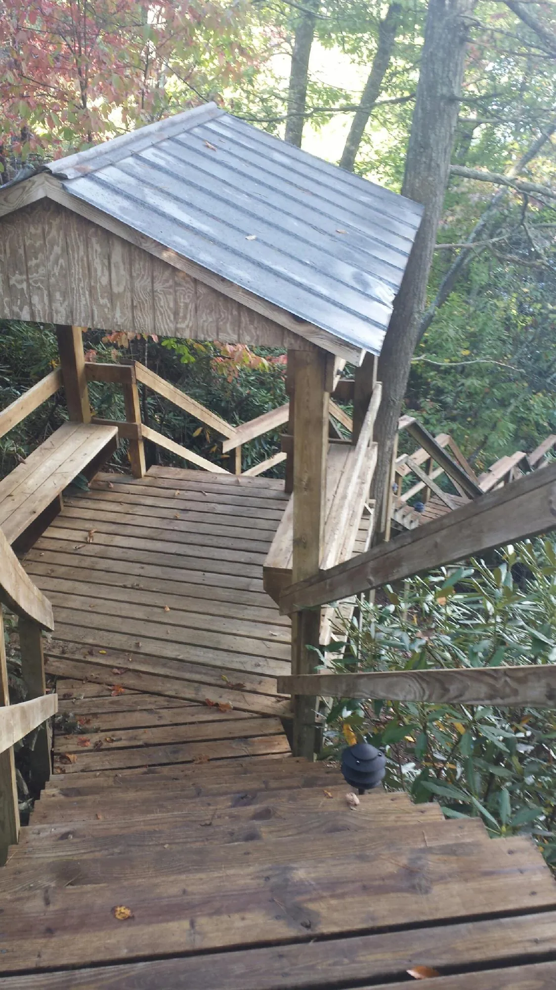 Metal roofed shelter over wooden steps on a wooded walkway — Skylight Repair & Installation work by our crew in Upsala
