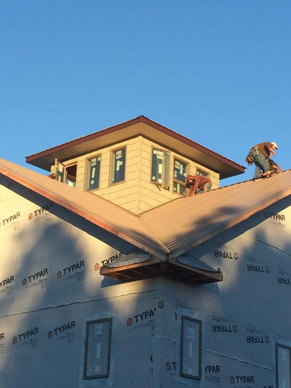 Roofers working around a rooftop cupola on a new metal roof at sunset — Roof Waterproofing in Upsala by Roofing Brothers
